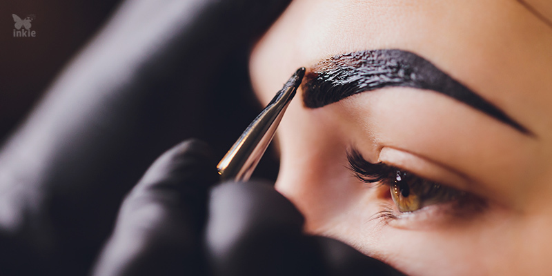 Profissional realizando uma técnica de micropigmentação de sobrancelha